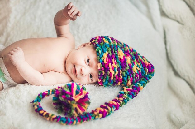 Pasgeboren baby in New Year's gnome Cap legt op een witte deken.