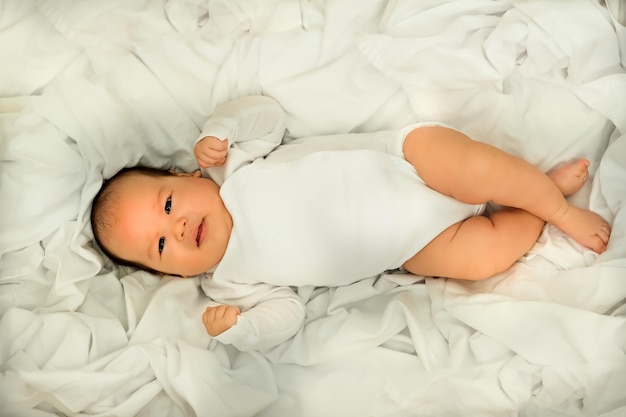 Pasgeboren baby lacht en lacht toont emoties baby ligt op een witte doek