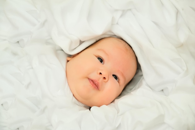 Pasgeboren baby lacht en lacht toont emoties baby ligt op een witte doek