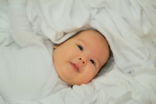 Pasgeboren baby lacht en lacht toont emoties baby ligt op een witte doek