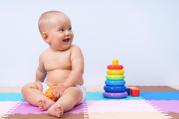 Pasgeboren baby lacht en speelt met een rubberen bal in de speelkamer