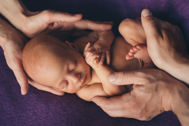 Pasgeboren baby liggend op de handen van ouders. Imitatie van een baby in de baarmoeder.