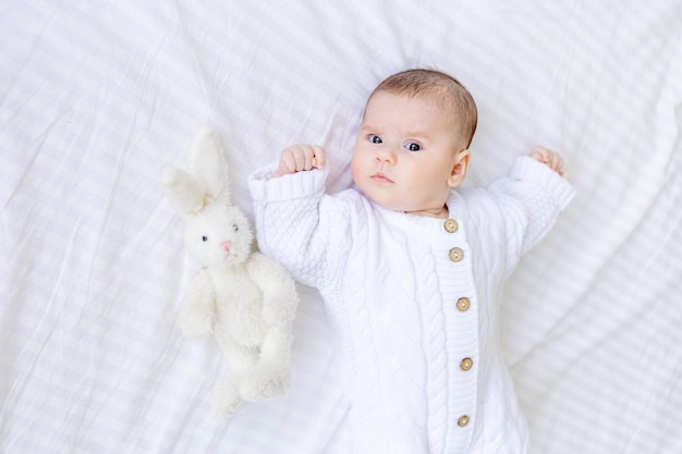 Pasgeboren baby ligt in een wieg in een witte warme jumpsuit op een wit geïsoleerd katoenen bed gezonde baby slaap close-up