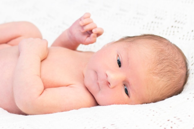 Pasgeboren baby ligt in het bed en glimlacht