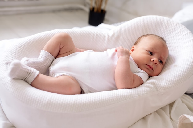 Pasgeboren baby ligt thuis in een cocon op het bed in de slaapkamer