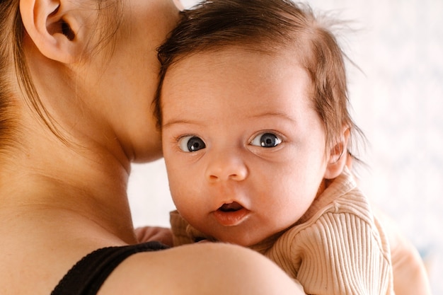 Foto pasgeboren baby met open ogen in mama's armen zijaanzicht