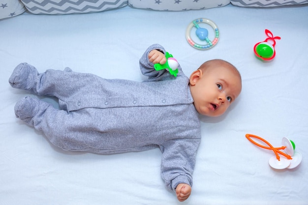 Pasgeboren baby op bed naast liggende speelgoedrammelaars