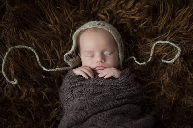 Pasgeboren baby slaapt in een donkere vacht close-up