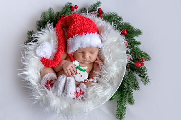 Pasgeboren baby slaapt in kerstaccessoires op een witte achtergrond, het concept van Kerstmis en Nieuwjaar