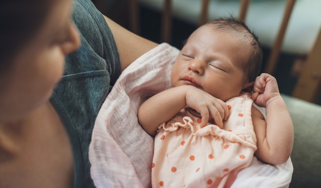 Pasgeboren baby slaapt in veiligheid terwijl moeder haar vasthoudt en lacht