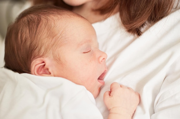 Pasgeboren baby slaapt op de borst van de moeder