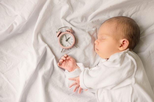 Pasgeboren baby slapen in een omslag op witte deken