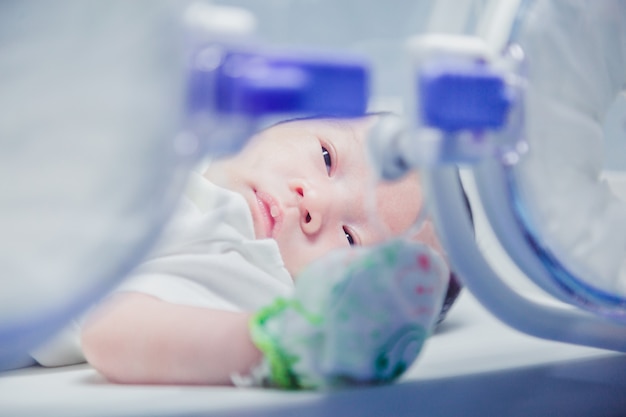 Pasgeboren babyjongen bedekt met vertix binnen incubator.