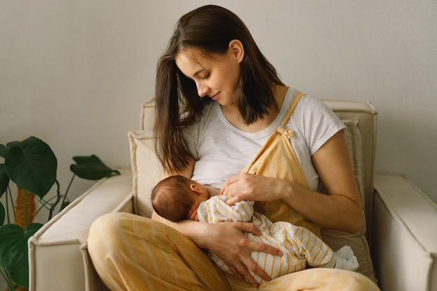 Pasgeboren babyjongen die melk uit de borst van moeder zuigt