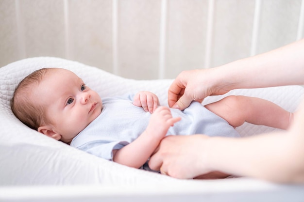 Pasgeboren babyjongen liggend in de kinderkamercocon met blauwe kleren op bed in de slaapkamer thuis op zoek naar een lieve moeder