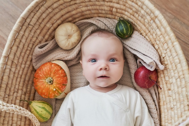 Pasgeboren babyjongen ligt in rieten wieg met pompoenen en appels. Gelukkig moederschap en vaderschap. Kraamkliniek en kliniek. Vader en moeder dag. Herfst achtergrond. Dankzegging, halloween