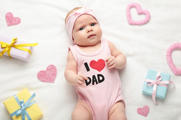 Pasgeboren babymeisje in t-shirt met inscriptie ik hou van vader camera kijken. Valentijnsdag