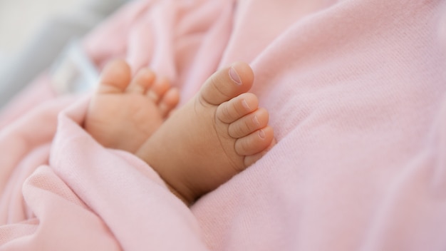 Pasgeboren babyvoetjes gewikkeld in een pastelroze deken