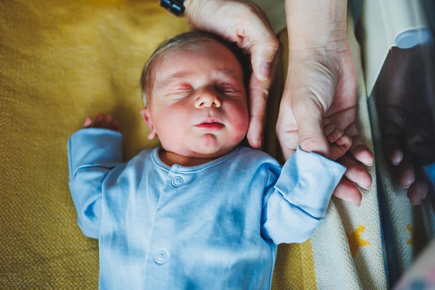 Pasgeboren jongen in de armen van zijn moeder en vader die op hun armen liggen close-up top view Jonge ouders houden hun kleine baby gezonde levensstijl vaderschap