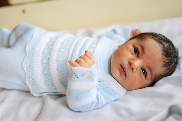 Pasgeboren jongen in het ziekenhuis op de eerste dag van zijn leven die voor het eerst zijn ogen opent