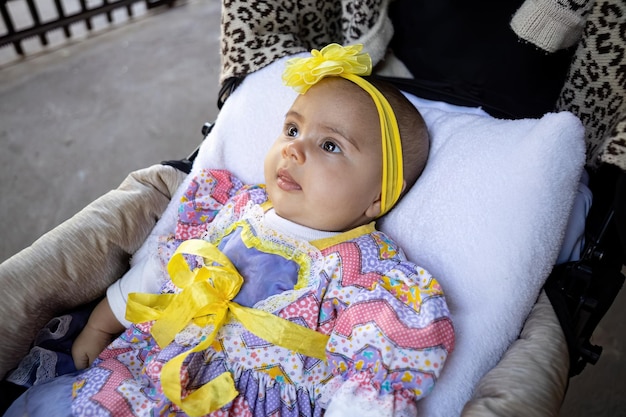 pasgeboren kind meisje in de kinderwagen met feestkleding en gele strik op haar hoofd