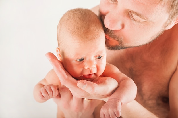 Pasgeboren op het bed met zijn vader close-up. Het concept van de relatie tussen kinderen en ouders vanaf de geboorte.