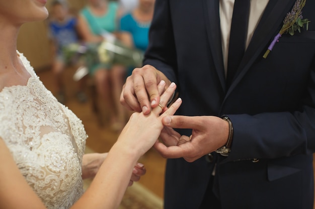 Pasgetrouwden wisselen ringen uit, bruidegom legt de ring op de hand van de bruid in het huwelijksregister