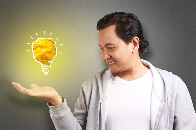 Photo pasian man smiling happy with bright light bulb lamp made of paper symbol of idea and innovation