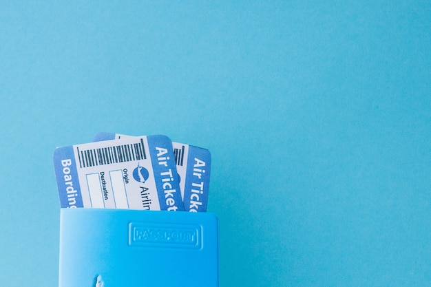 Foto paspoort en vliegticket in vrouwenhand op een blauw