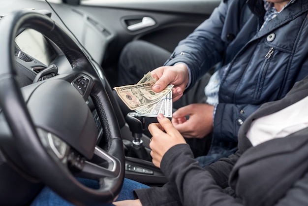 Passagier die dollarbankbiljetten geeft aan een chauffeur