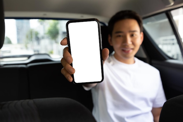 Passagier die lege applicatie op mobiele telefoon toont terwijl hij op de achterbank in de auto zit