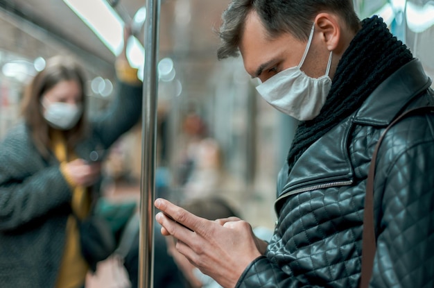 Passagier met een beschermend masker leest een bericht op zijn smartphone. coronavirus in de stad