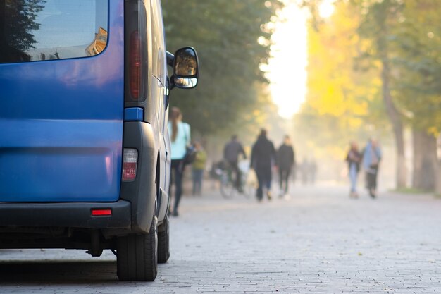 Passagier van auto geparkeerd op een steegje straatkant van de stad met wazig wandelende voetgangers in de herfst.