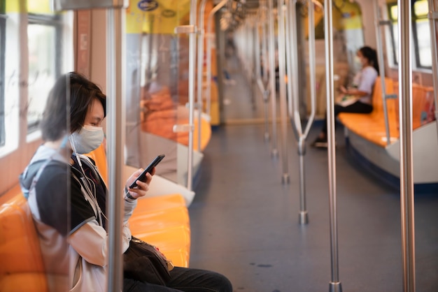 Passagiers die naar mobiele telefoons kijken terwijl ze op de elektrische trein BTS in Bangkok Thailand zitten