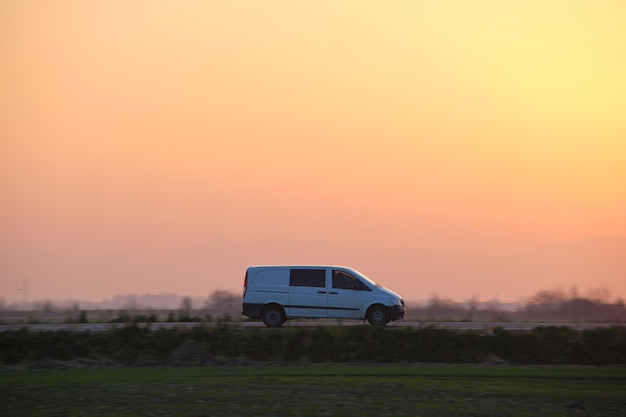 Passagiersbus rijdt snel op intercityweg bij zonsondergang Snelwegverkeer in de avond