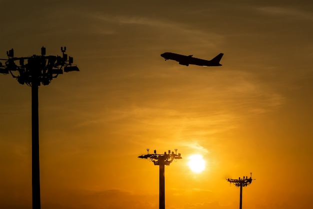 Passagiersvliegtuig stijgt op tijdens een prachtige zonsopgang Lampentoren van schijnwerpers op de pilaren