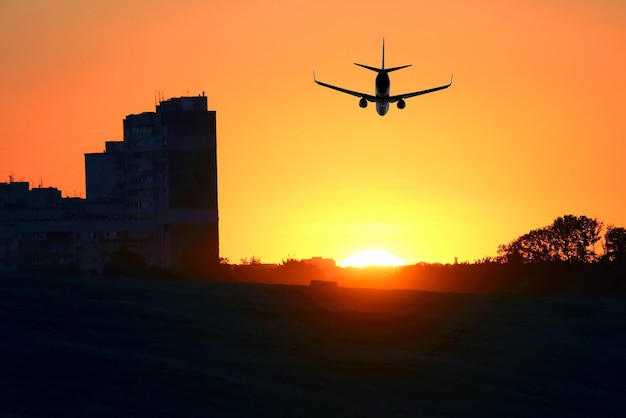 Passagiersvliegtuig vliegt bij zonsondergang op het oppervlak van hoogbouw