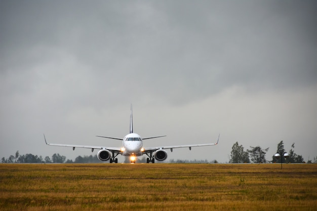 Passagiersvliegtuigen met lichten gaan naar de startbaan op het vliegveld in de avond in de regen