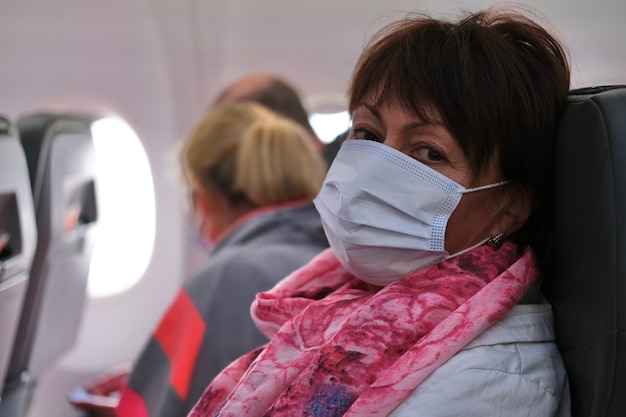 Passagiersvrouw met medisch masker in vliegtuig