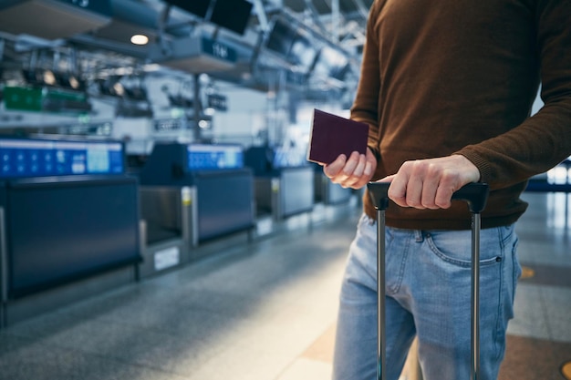 공항 의 체크인 카운터 에 있는 승객 은 가방 과 여권 을 들고 있는 젊은 남자 의 손 에 있다