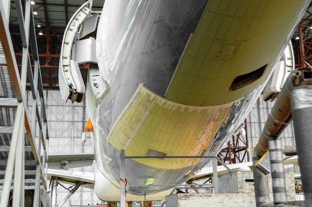 Passenger aircraft on maintenance and fuselage repair after damage in airport hangar.