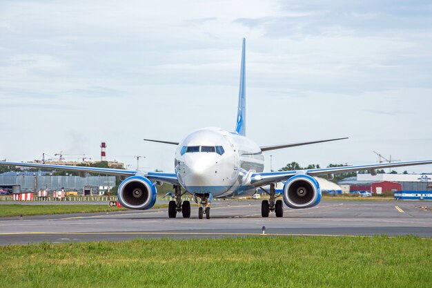 アスファルトの空港のエプロンでタキシングしている旅客機は、目に見えるマーキングです。