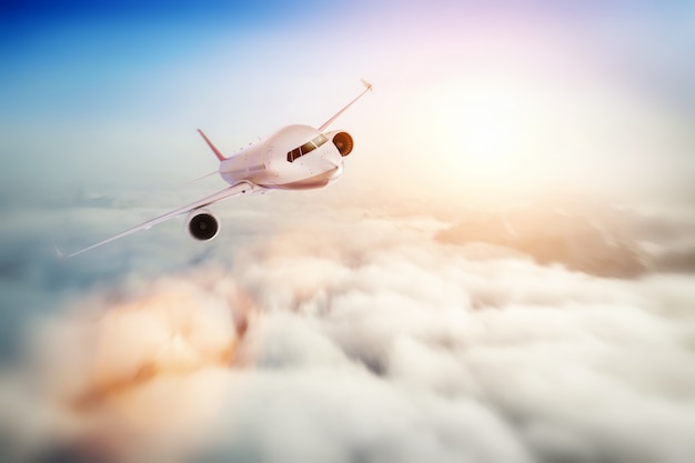 Volo dell'aeroplano del passeggero al tramonto, cielo blu.