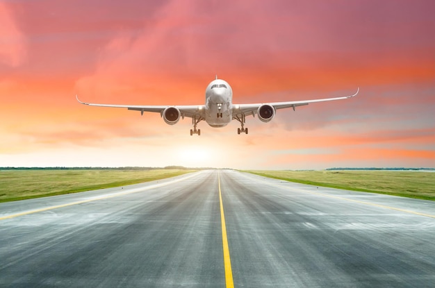 Photo passenger airplane landing on a runway in the evening during a bright red sunset