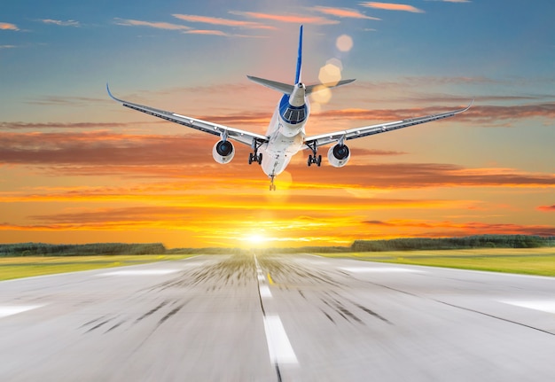 Passenger airplane landing at sunset on a runway.