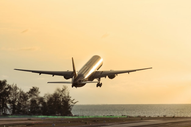 旅客機は日没時に海上で離陸します。飛行機のシルエットが飛び上がる。休暇、航空、旅行の概念