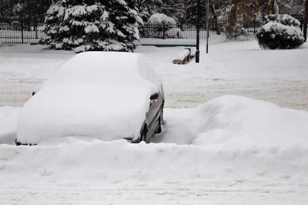 The passenger car is parked under the snow.