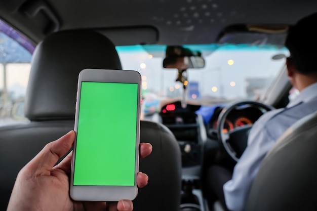 タクシーの後部座席にあるスマートフォンを使用してモバイルアプリケーションを利用する乗客。