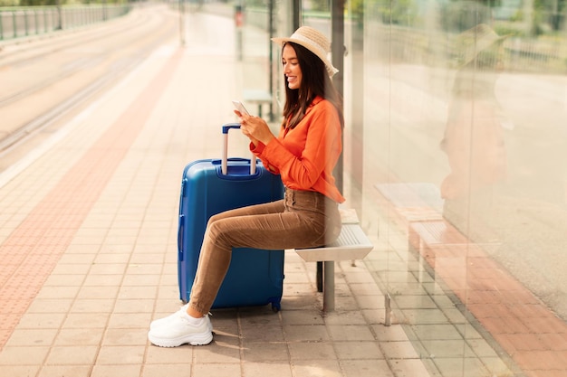 passenger lady using cellphone sitting at tram stop