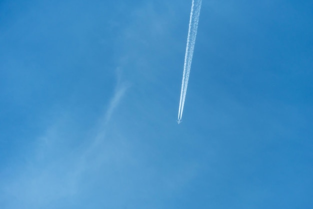 Aereo passeggeri su uno sfondo di cielo azzurro un lungo flusso di fumo fuoriesce dai motori di un aereo a reazione sentiero reattivo di inversione di condensazione